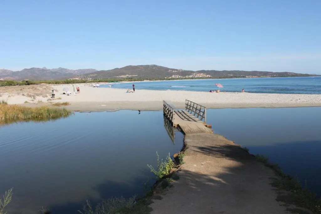 Spiaggia con laguna, passerella in legno e vista sulle montagne
