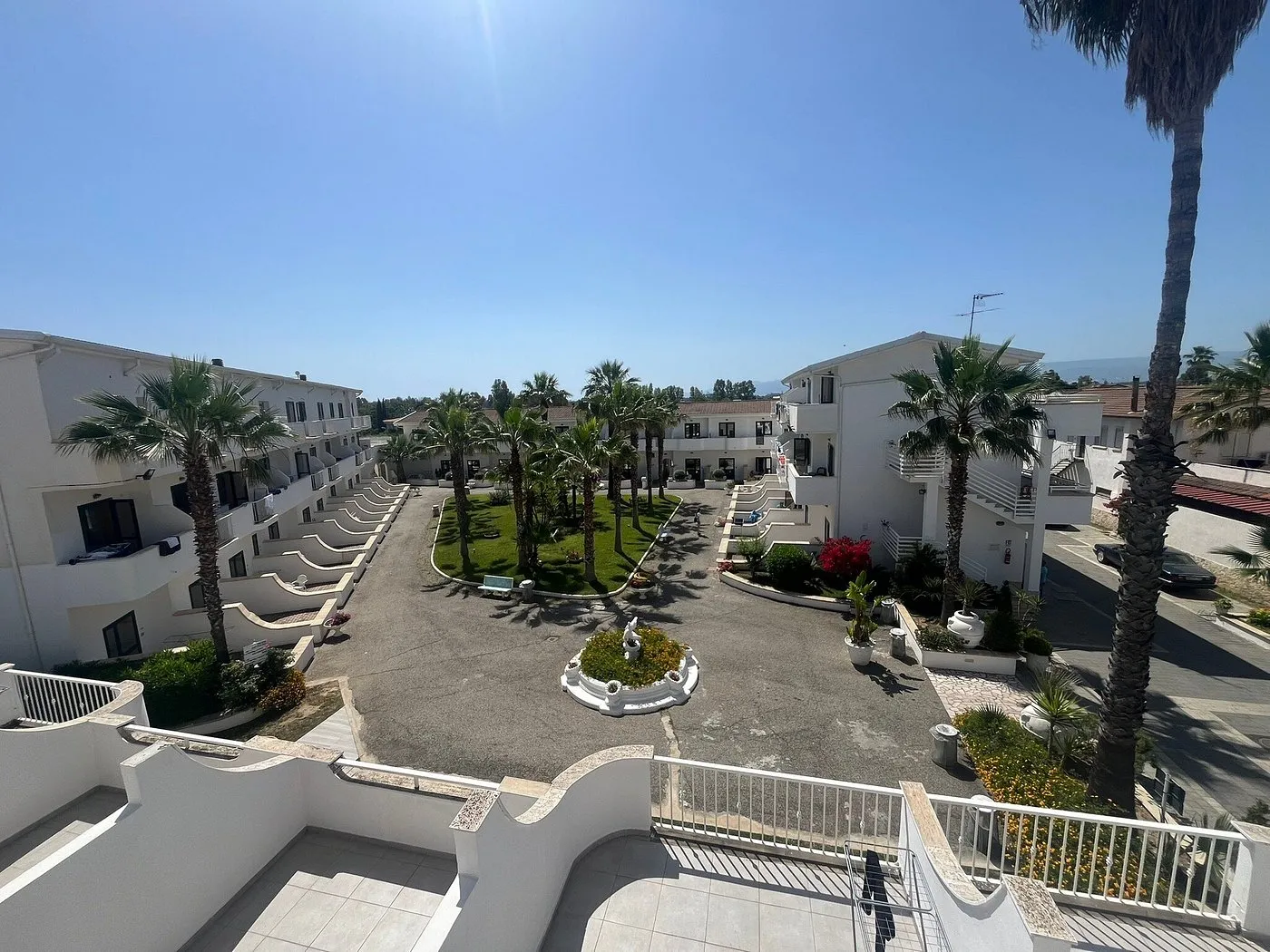 Vista panoramica del cortile interno del residence con palme e fontana centrale