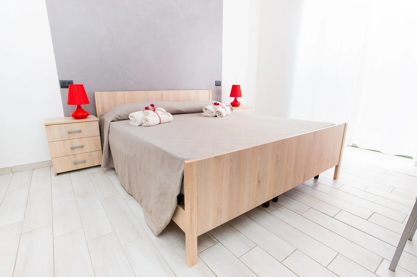 Camera da letto luminosa con letto matrimoniale in legno e lampade rosse