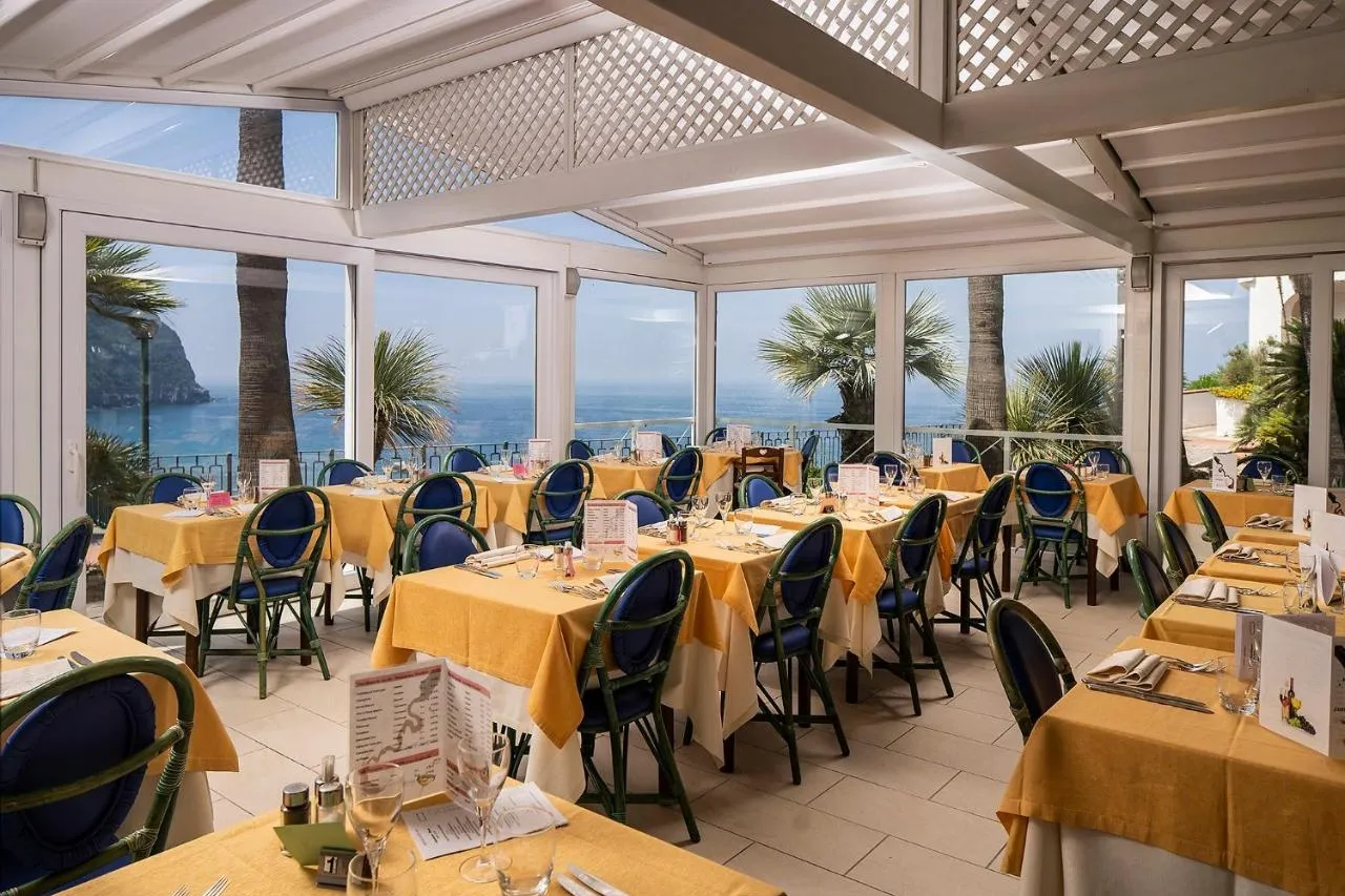 Sala ristorante con vetrate panoramiche sul mare, tovaglie gialle e sedie blu e verdi