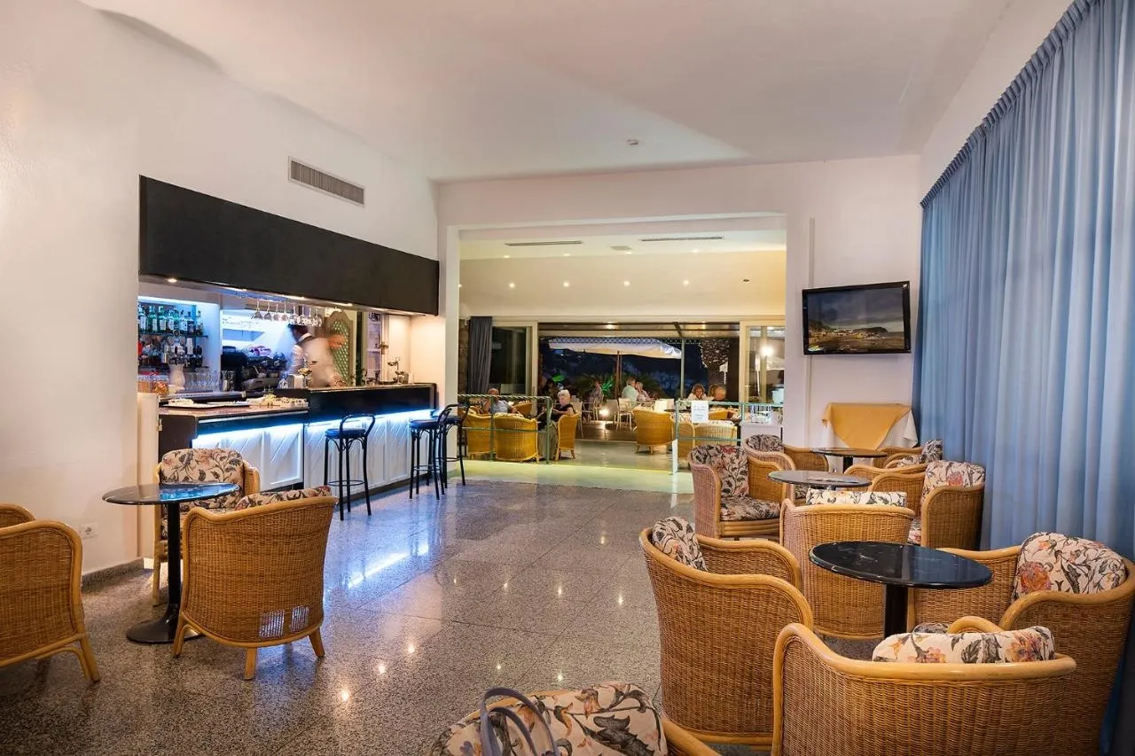 Bar interno dell'hotel con poltrone in vimini, bancone illuminato e vista sulla terrazza