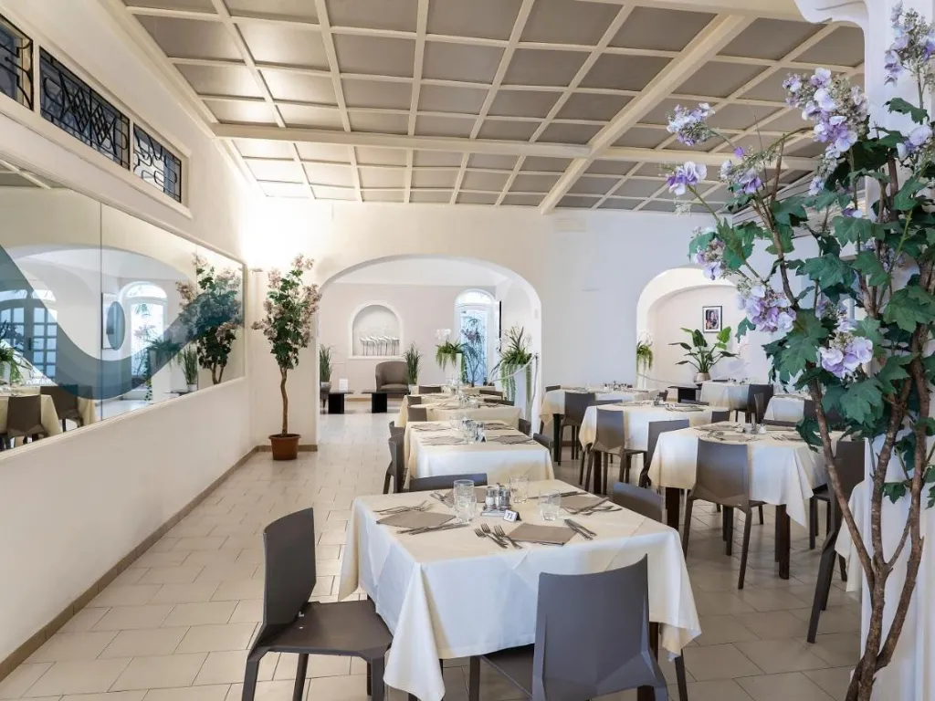 Sala ristorante elegante con tavoli apparecchiati e decorazioni floreali