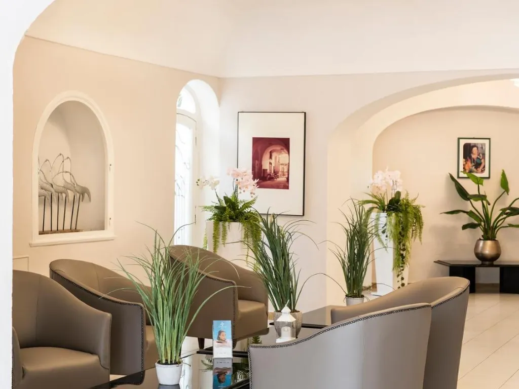 Area lounge dell'hotel con poltrone, piante verdi e quadri alle pareti