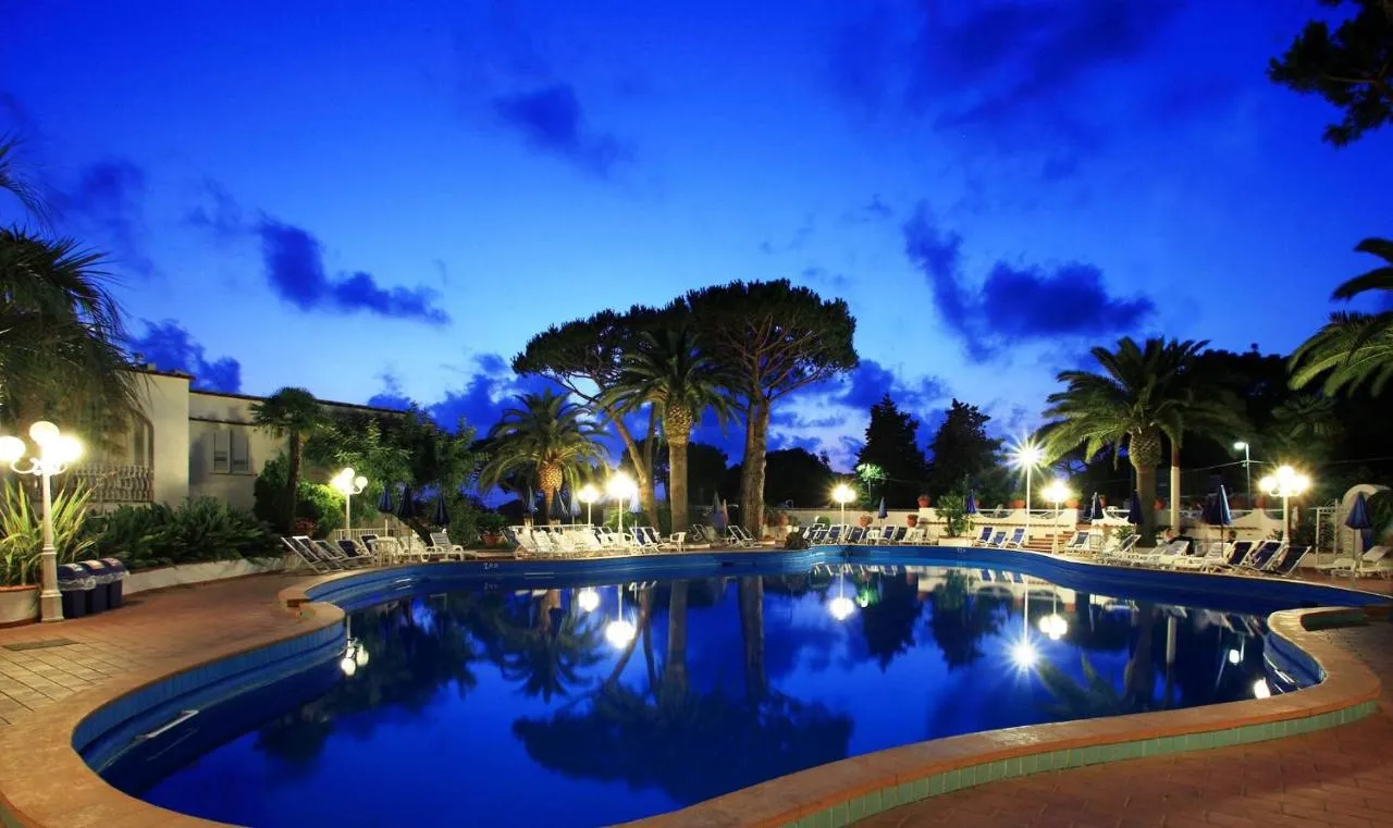 Piscina esterna al crepuscolo con cielo blu intenso e palme illuminate