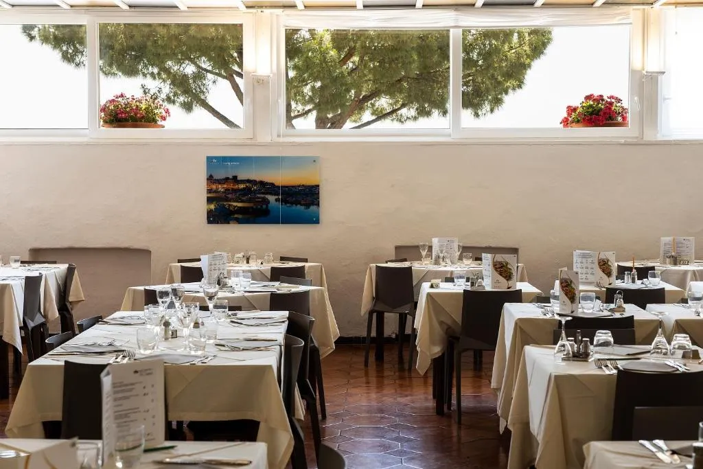 Sala da pranzo con tavoli apparecchiati e finestre affacciate sul verde