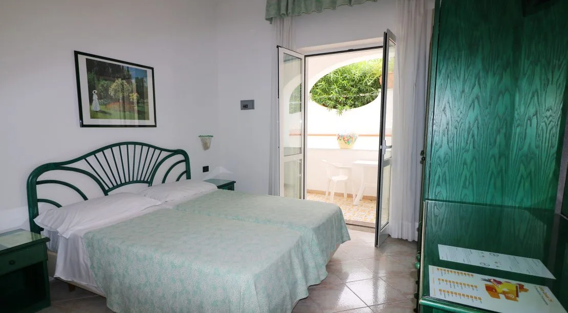 Camera con letto matrimoniale, testiera verde e accesso al terrazzo