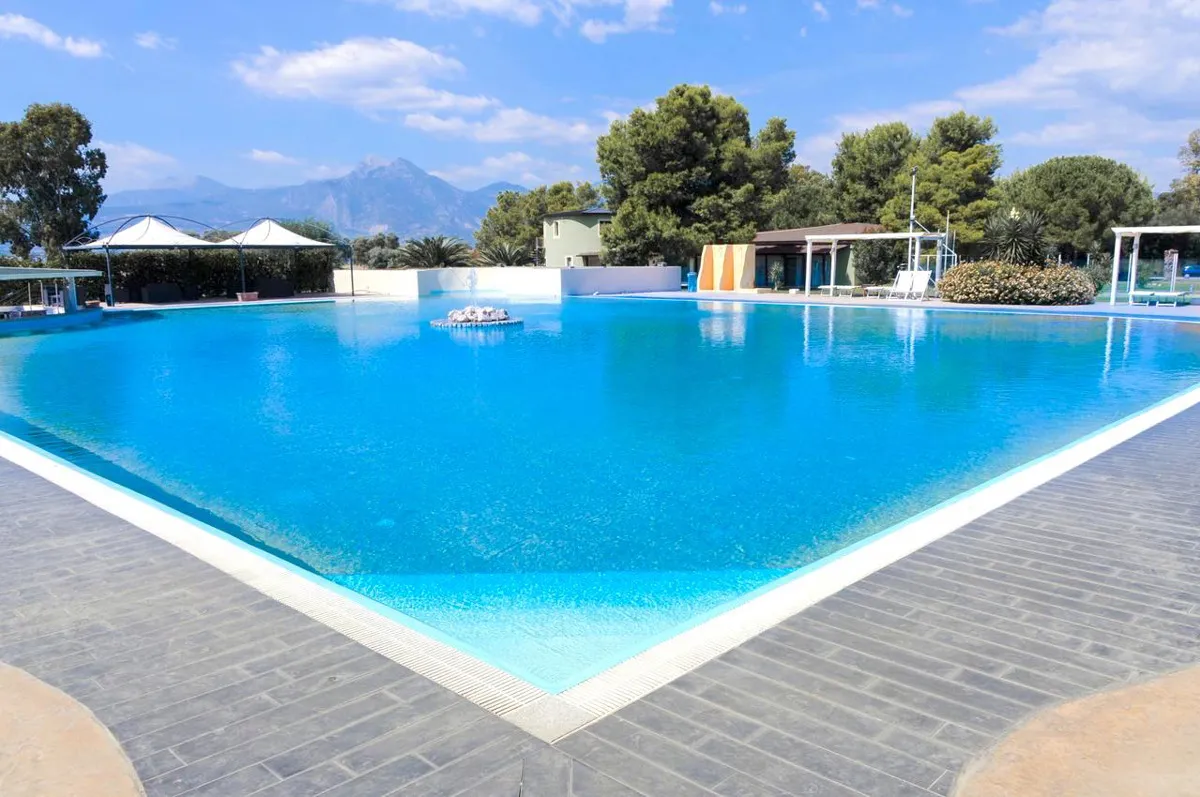 Piscina a sfioro con acqua blu, vista panoramica su montagne e vegetazione