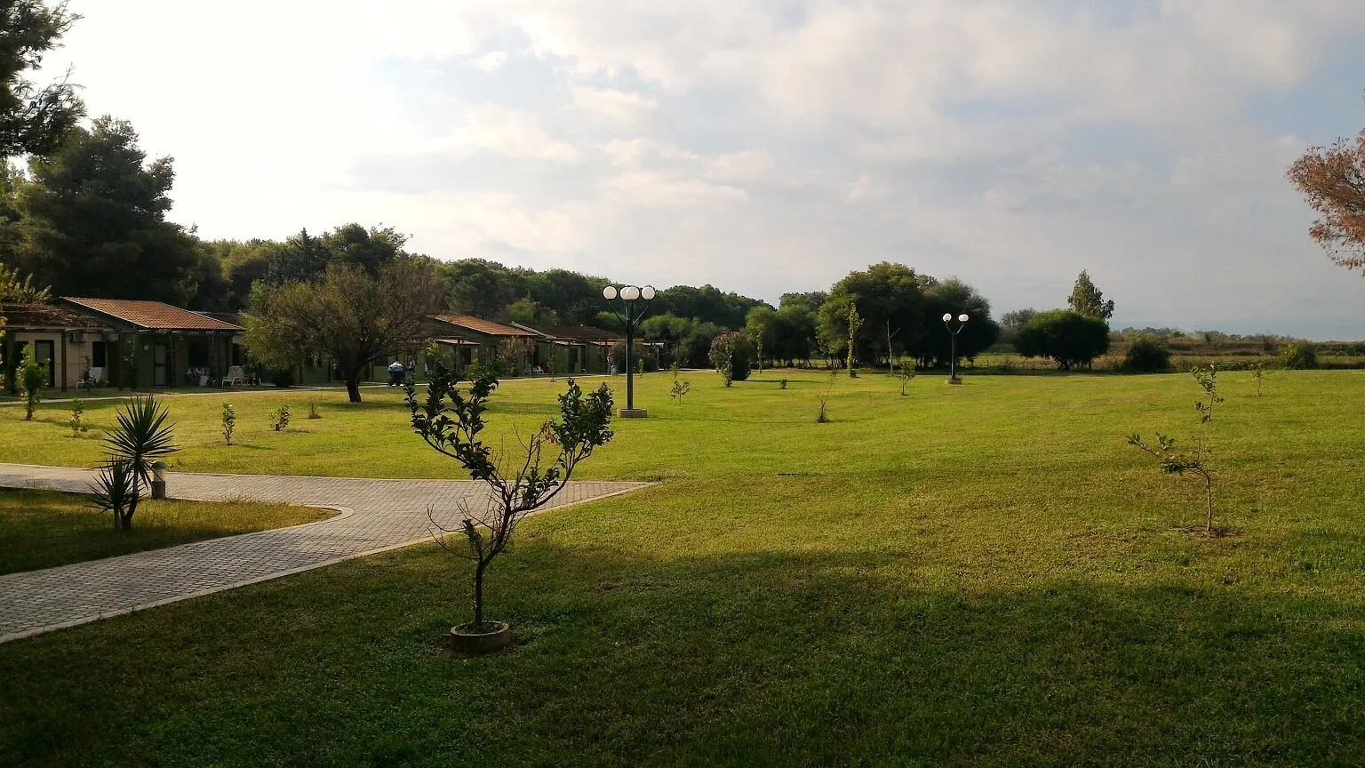 Vasto prato verde con villette e lampioni immerso nella natura del villaggio