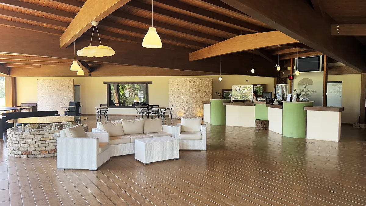 Hall accogliente con soffitto in legno, divani bianchi e reception