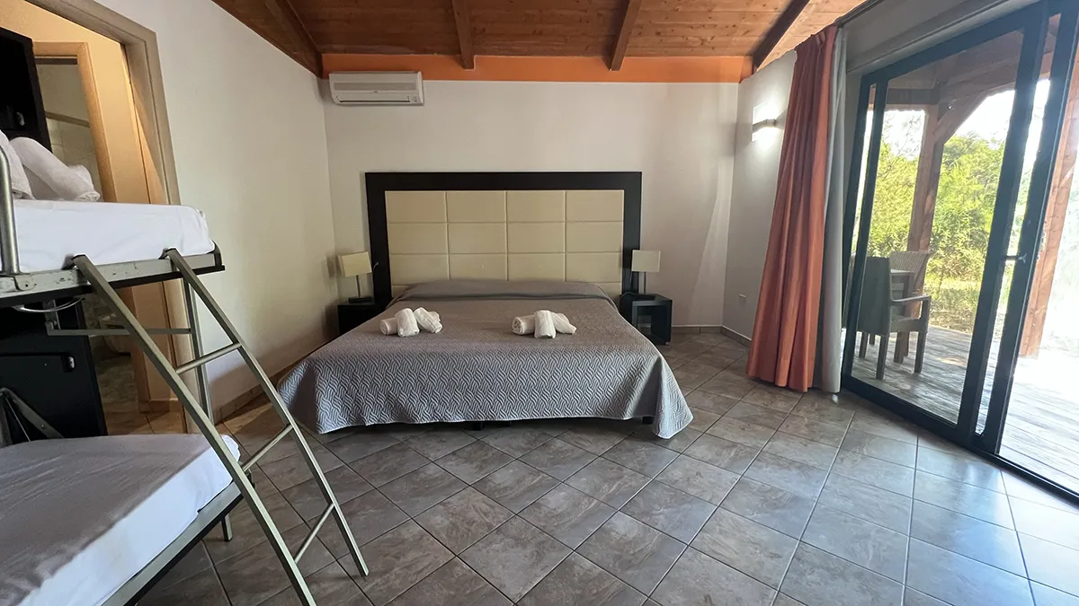 Camera con letto matrimoniale, letto a castello e ampia vetrata sulla veranda