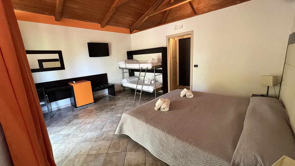 Camera spaziosa con letto matrimoniale, letto a castello, scrivania e TV