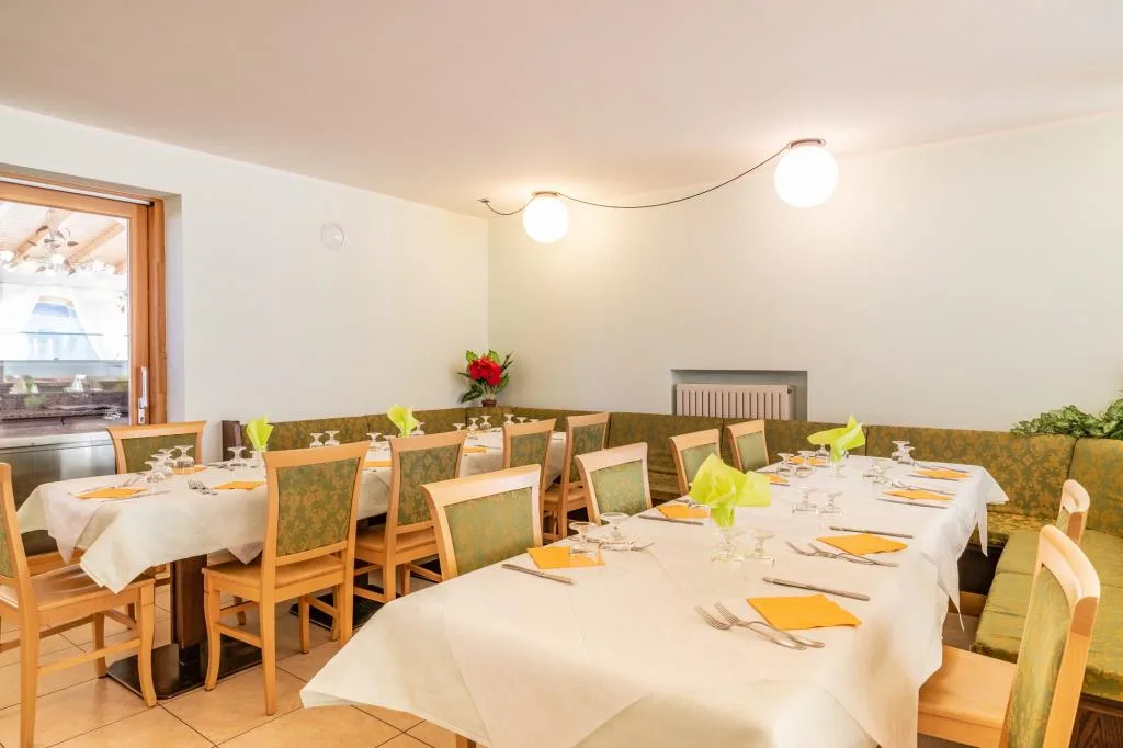 Sala da pranzo con tavoli apparecchiati, tovaglie bianche e tovaglioli colorati