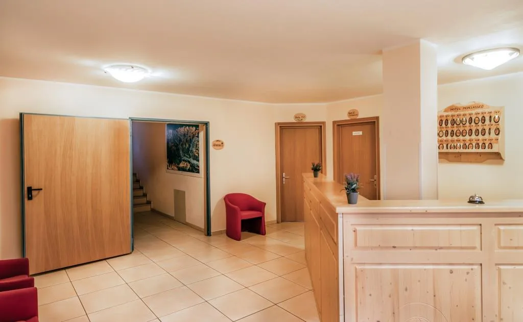 Hall dell'hotel con reception in legno, pavimento in piastrelle e poltrona rossa