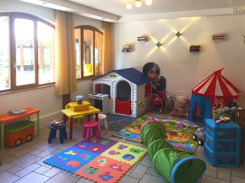 Sala giochi per bambini con casetta, tappeti colorati e giocattoli