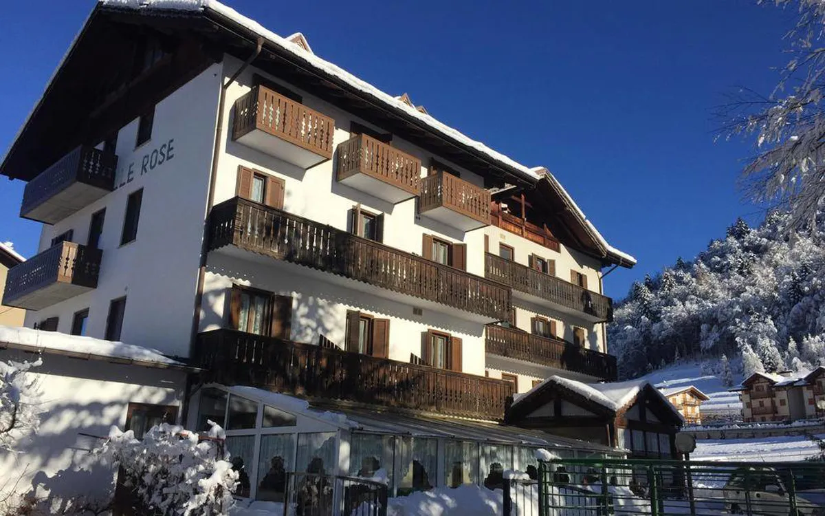 Facciata dell'hotel Le Rose con balconi in legno e paesaggio innevato