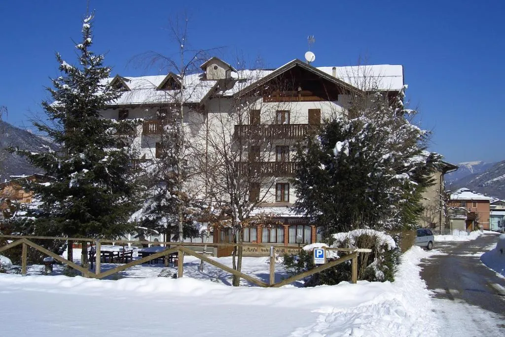 Esterno dell'hotel innevato con alberi coperti di neve e cielo azzurro in inverno