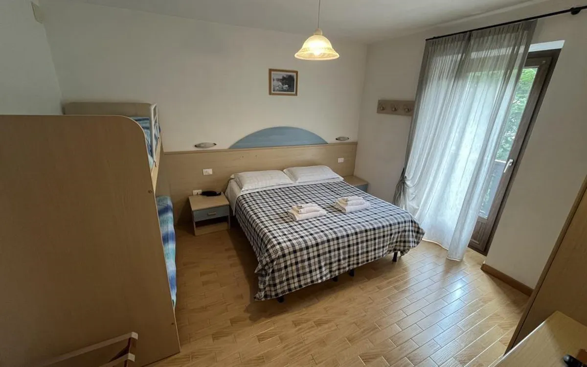 Camera con letto matrimoniale, copriletto a quadri e accesso al balcone