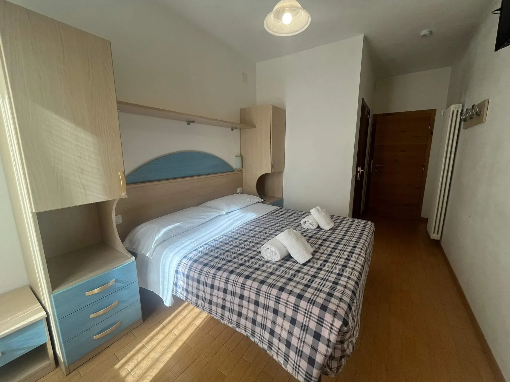 Camera con letto matrimoniale, mobili a ponte azzurri e pavimento in legno
