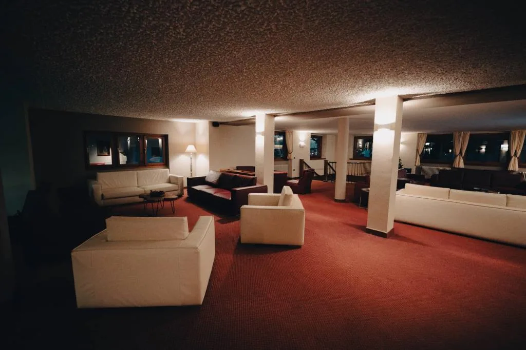 Ampia hall con divani bianchi e in pelle e moquette rossa