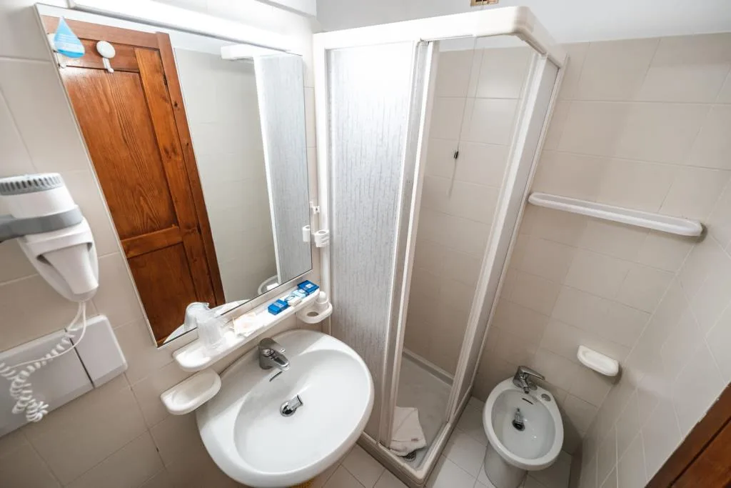 Bagno con lavabo, specchio, doccia e bidet, rivestimento chiaro