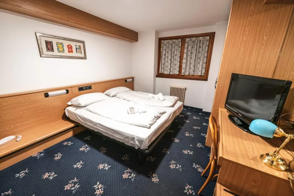 Camera matrimoniale con letto, TV e lampada da tavolo azzurra