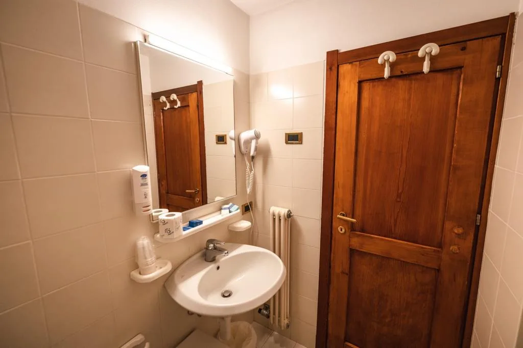 Bagno con lavabo, specchio illuminato e porta in legno