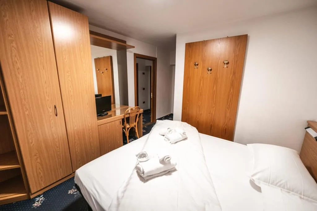 Camera con letto matrimoniale, armadi in legno e angolo scrivania