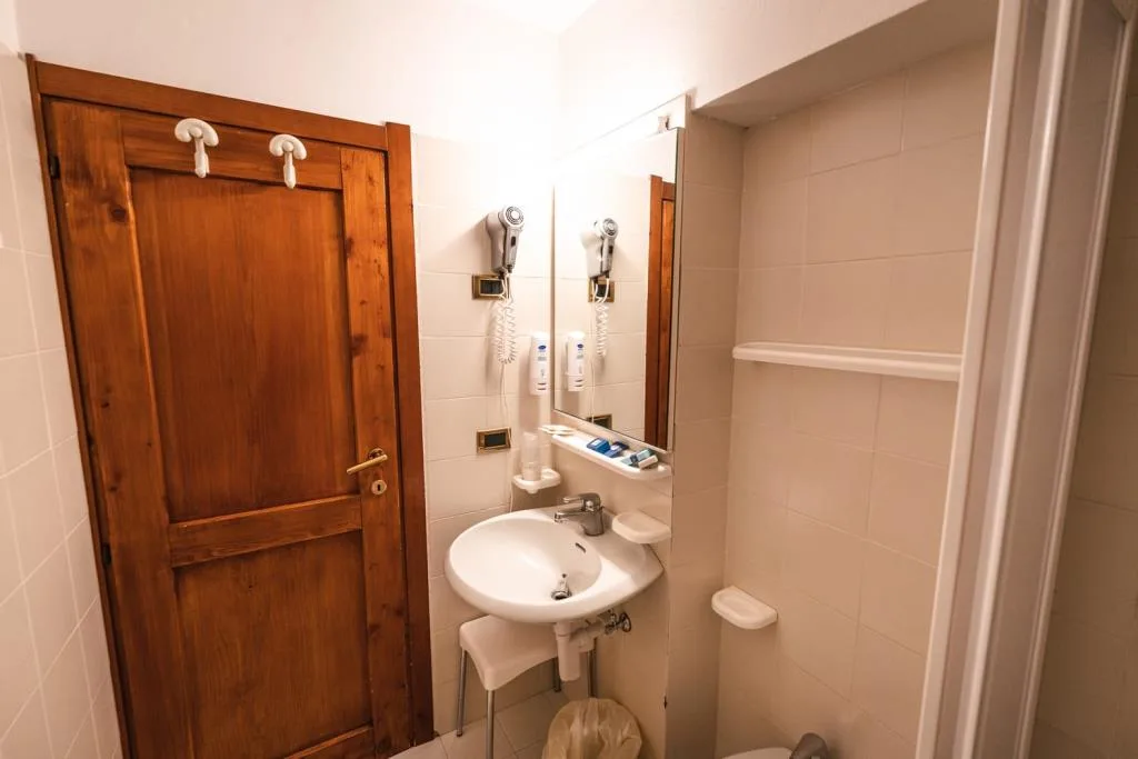 Bagno con lavabo, specchio e porta in legno