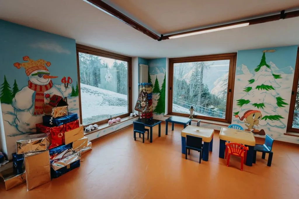 Sala giochi per bambini con pareti decorate e tavolini colorati