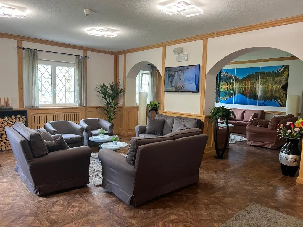 Sala soggiorno con divani, poltrone, TV e quadri panoramici di paesaggi montani