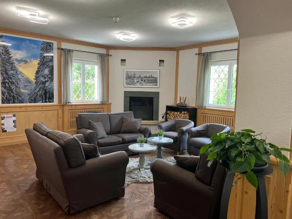 Sala relax con divani grigi, camino e immagine panoramica di bosco innevato