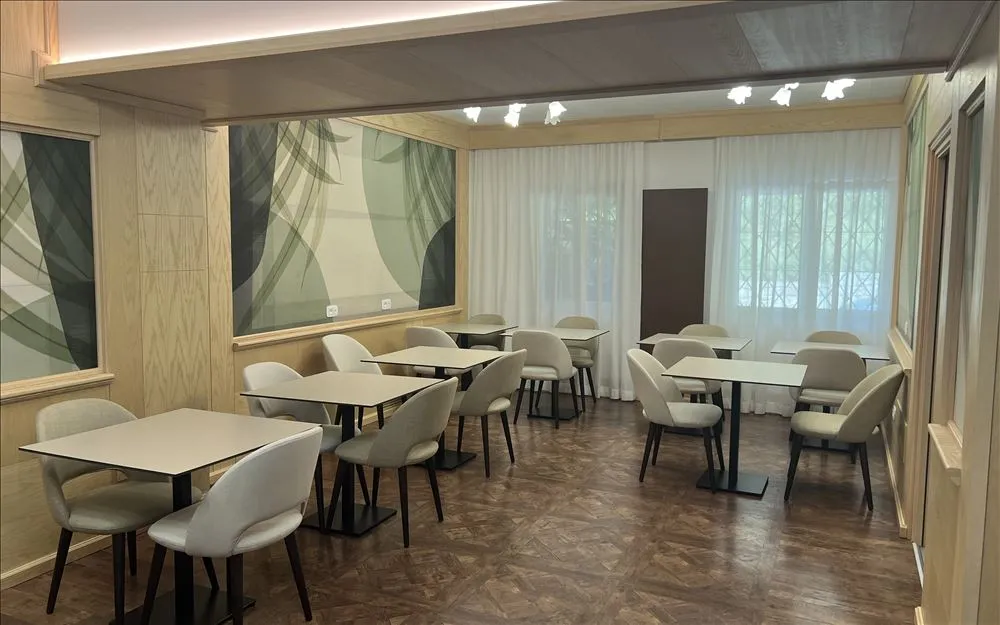 Sala da pranzo moderna con tavoli e sedie chiare e pareti decorate