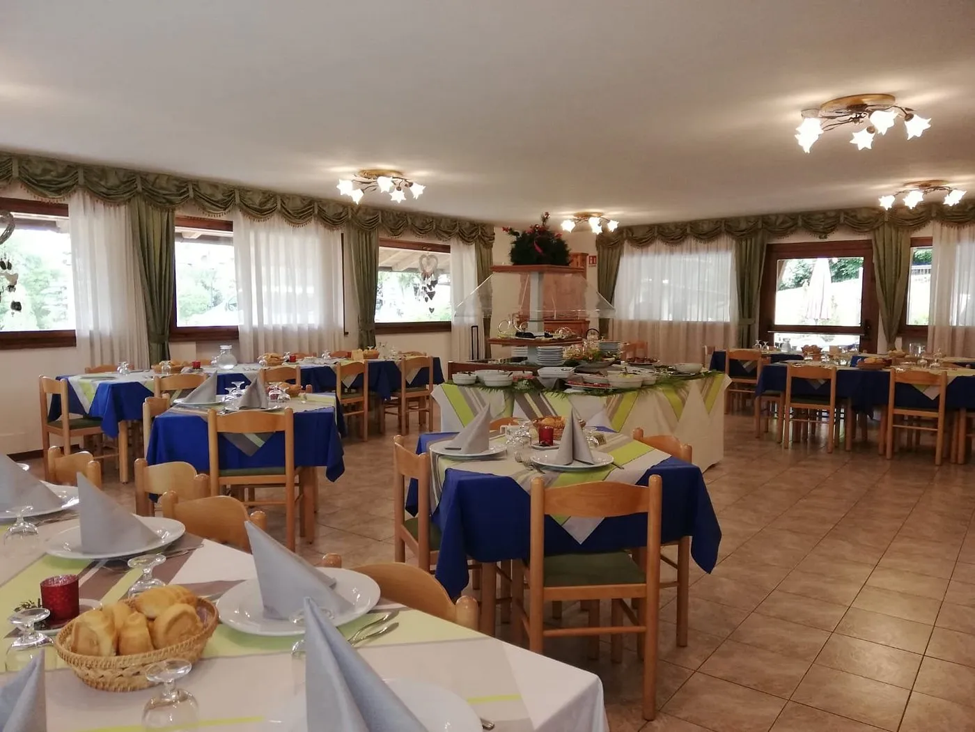 Sala ristorante con tavoli apparecchiati e buffet centrale vicino alle finestre
