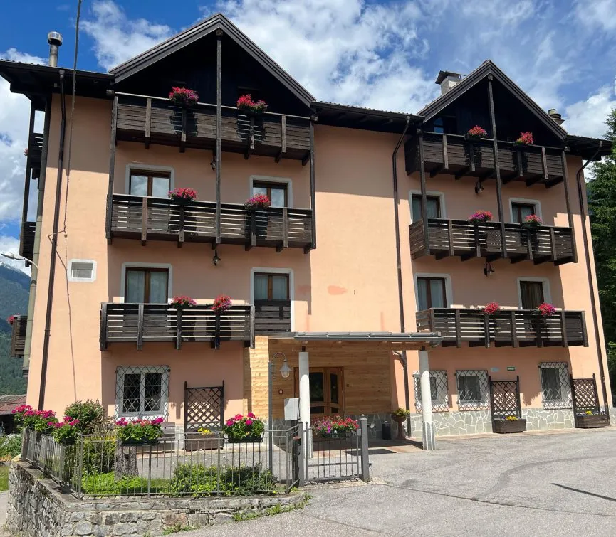 Facciata dell'hotel con balconi in legno e fioriere di gerani rossi