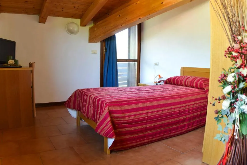 Camera mansardata con soffitto in legno, letto matrimoniale e TV