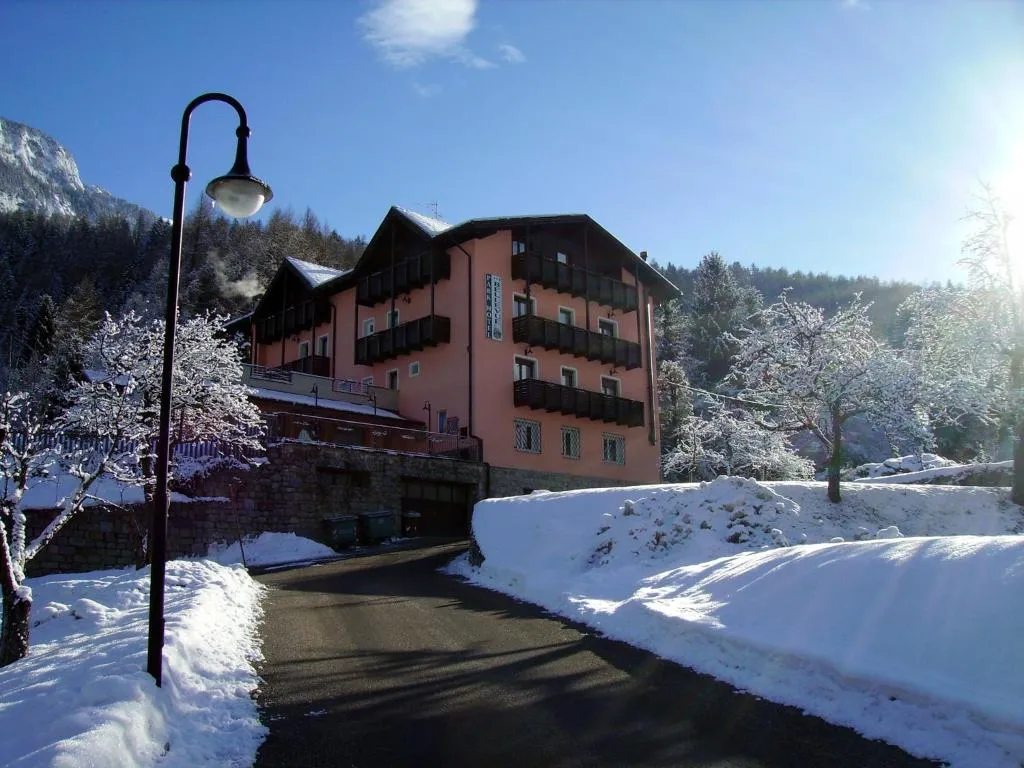 Strada e facciata dell'hotel sotto la neve con cielo azzurro