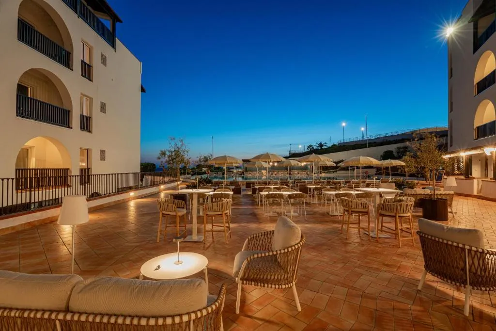 Area lounge esterna con poltrone e tavoli illuminati all'imbrunire