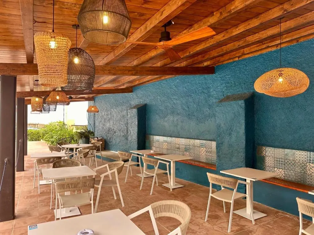 Sala ristorante interna con pareti azzurre, tavoli e lampadari in rattan