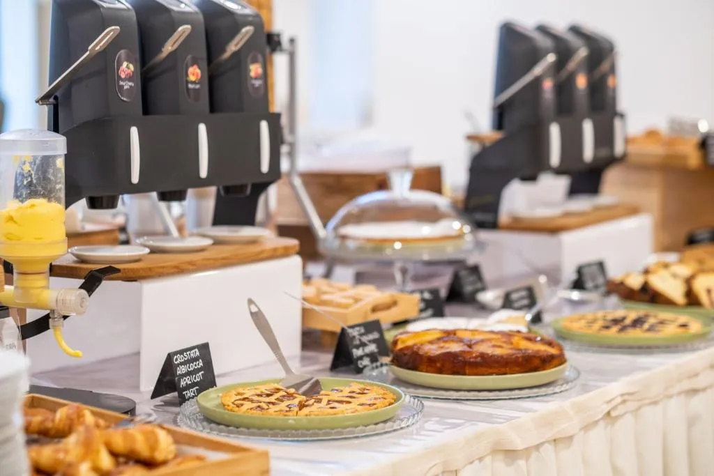 Buffet della colazione con crostate, torte e distributori di bevande
