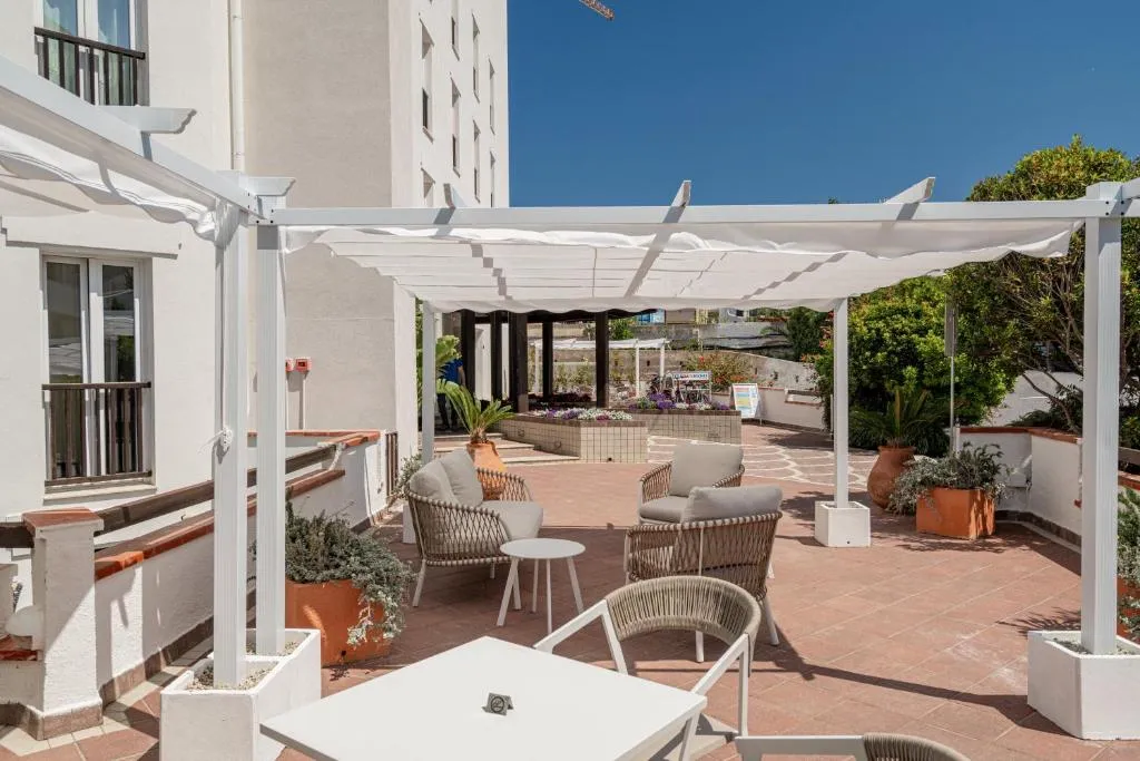 Terrazza esterna con pergola bianca, poltrone e piante in vaso