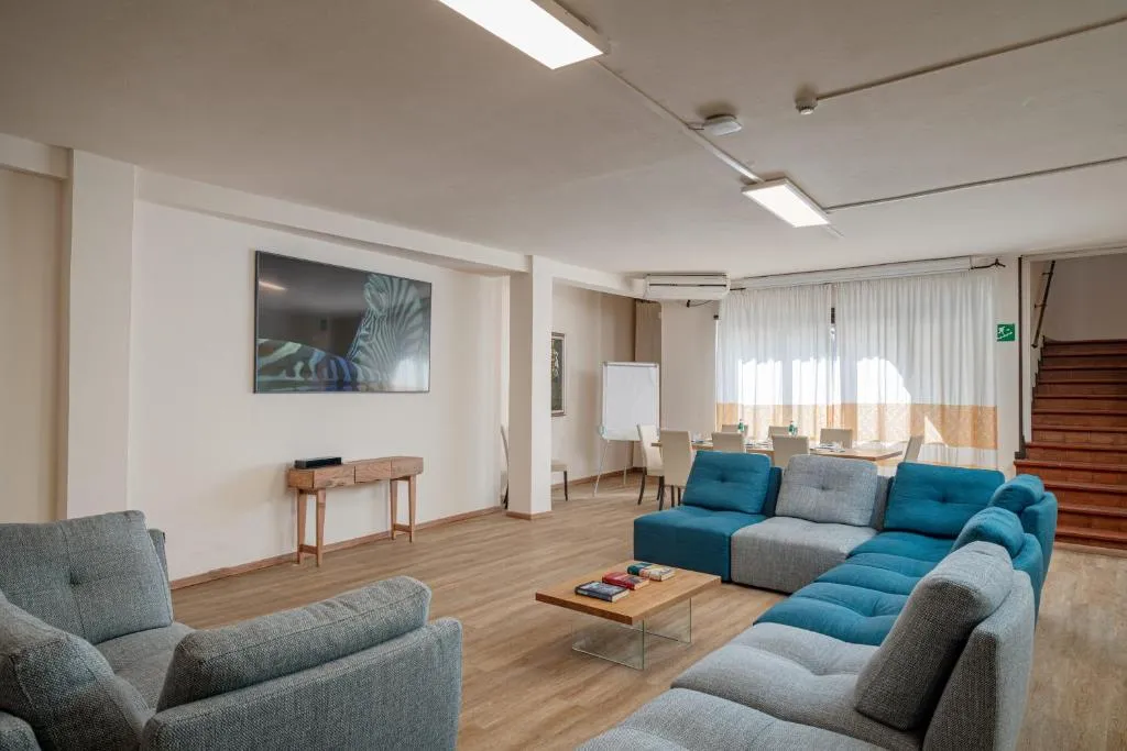Sala comune con divani, TV a parete e zona riunioni