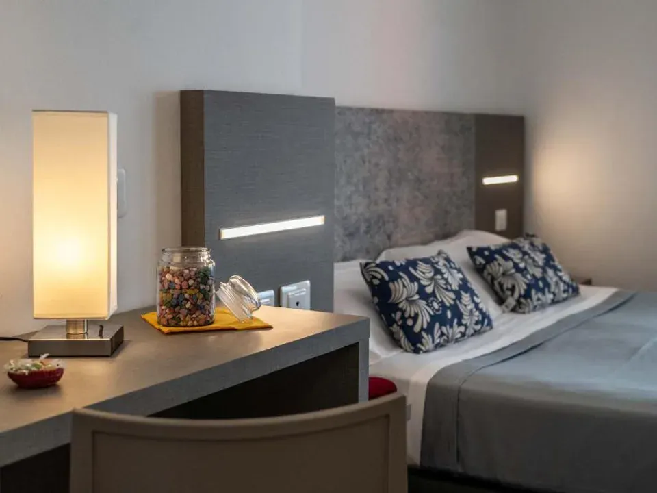 Dettaglio di camera con letto, comodino, lampada e cuscini decorativi blu