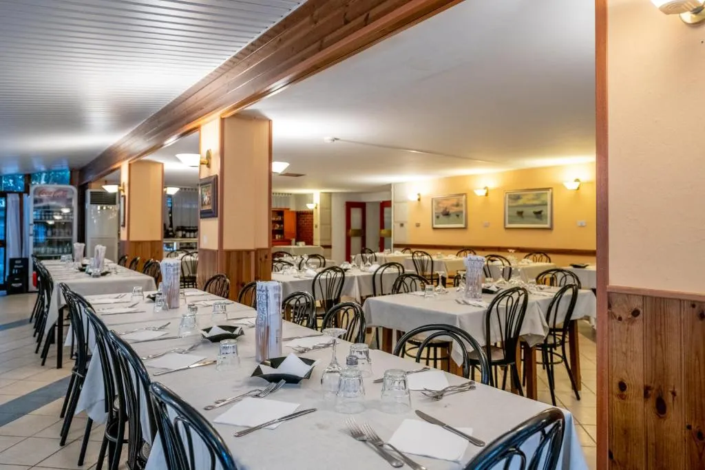 Sala ristorante interna con tavoli apparecchiati e arredo in legno