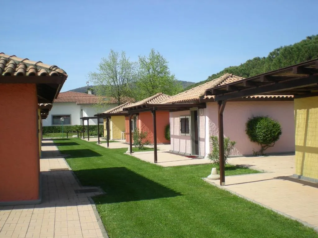 Vialetto tra bungalow colorati con verande in legno e prato curato