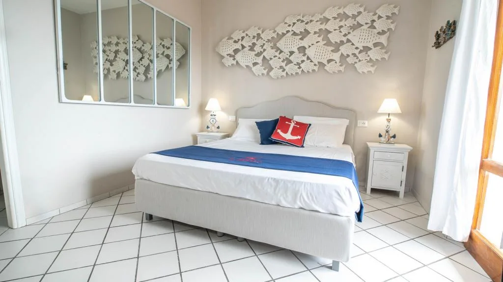 Camera con letto matrimoniale, decorazione di pesci bianchi a parete e comodini coordinati