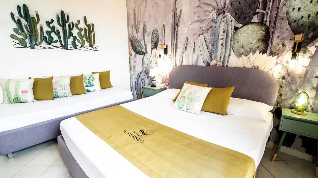 Camera con parete a tema cactus, letto matrimoniale e divano con cuscini decorati