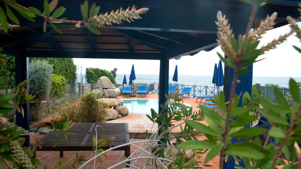Pergolato in legno con vista sulla piscina e sul mare circondato dal verde