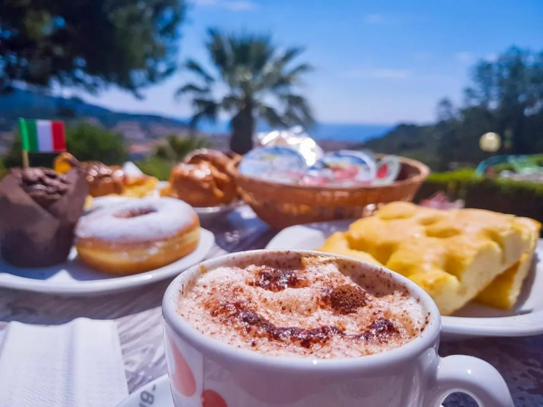 Cappuccino e dolci da colazione su tavolo all'aperto con vista panoramica sul mare