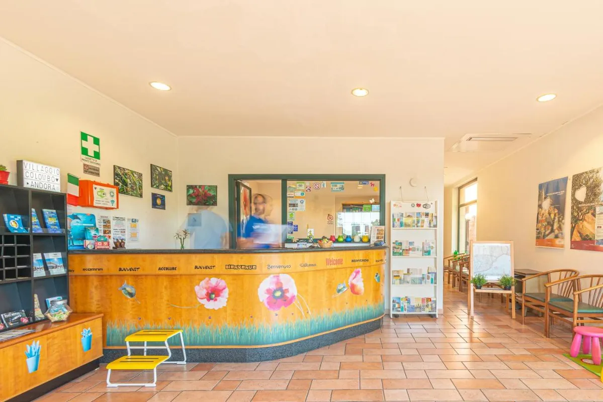 Interno della hall con bancone reception colorato e materiale informativo