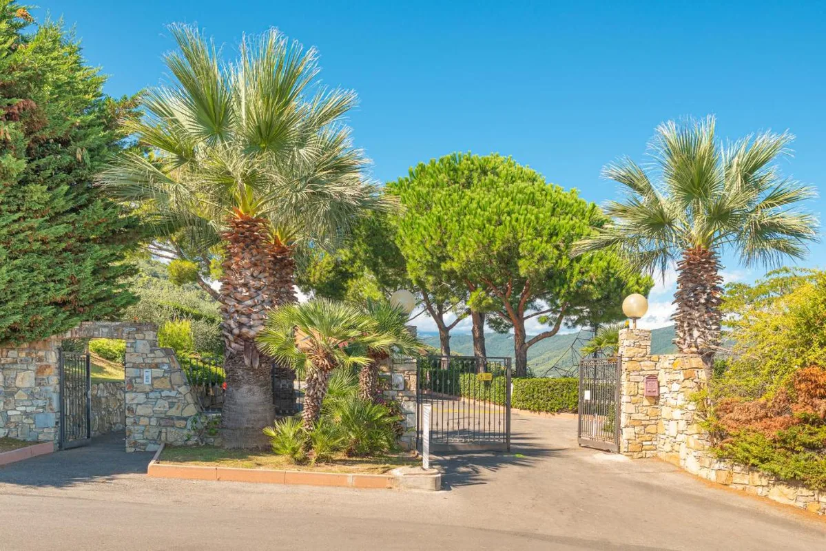 Ingresso del villaggio con cancello, palme e mura in pietra